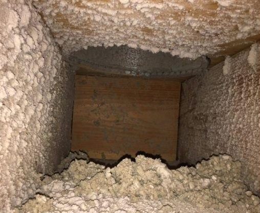 Inside an air duct before cleaning, packed with thick dust and debris
